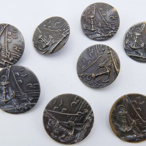 May include: Eight antique metal buttons with a nautical theme. Each button features a detailed design of a sailboat with an anchor and waves.