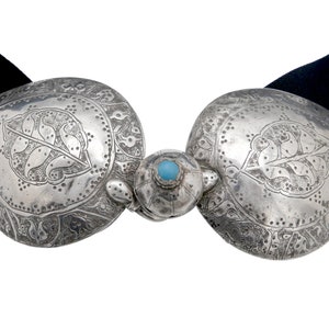 May include: A silver belt buckle with intricate floral designs and a turquoise stone in the centre.