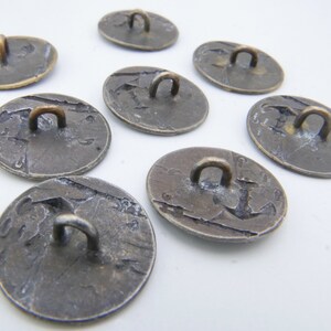 May include: Eight antique silver-toned buttons with a loop on the top. The buttons have a worn, aged appearance and are circular in shape.