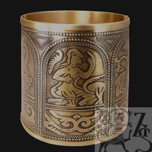 May include: A gold-colored metal cuff bracelet with intricate embossed designs. The bracelet features a central panel with a figure and animal, surrounded by ornate patterns and borders. The overall design suggests a historical or cultural theme.