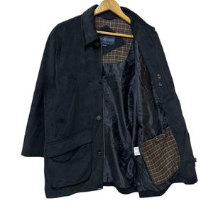 May include: A black corduroy jacket with a button fastening and a plaid lining. The jacket has a large pocket on the front and a smaller pocket on the inside.
