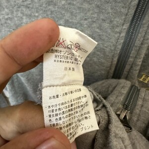 May include: Close-up of a gray cotton garment tag with black text. The tag reads "株オゾンコミティ HYSTERIC GL 東京都渋谷区千駄ヶ谷3 日本製" and includes washing instructions in Japanese.