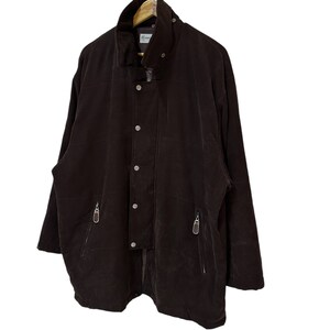 May include: A dark brown jacket with a high collar, a zip closure, and multiple pockets. The jacket has a slightly oversized fit and a relaxed silhouette.