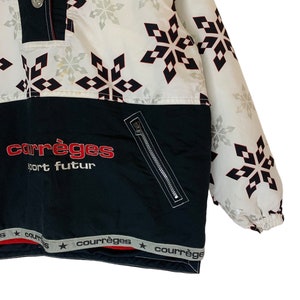 May include: A black and white ski jacket with a snowflake pattern. The jacket has a zipper closure and a red and white logo that says "courr&egrave;ges sport futur".