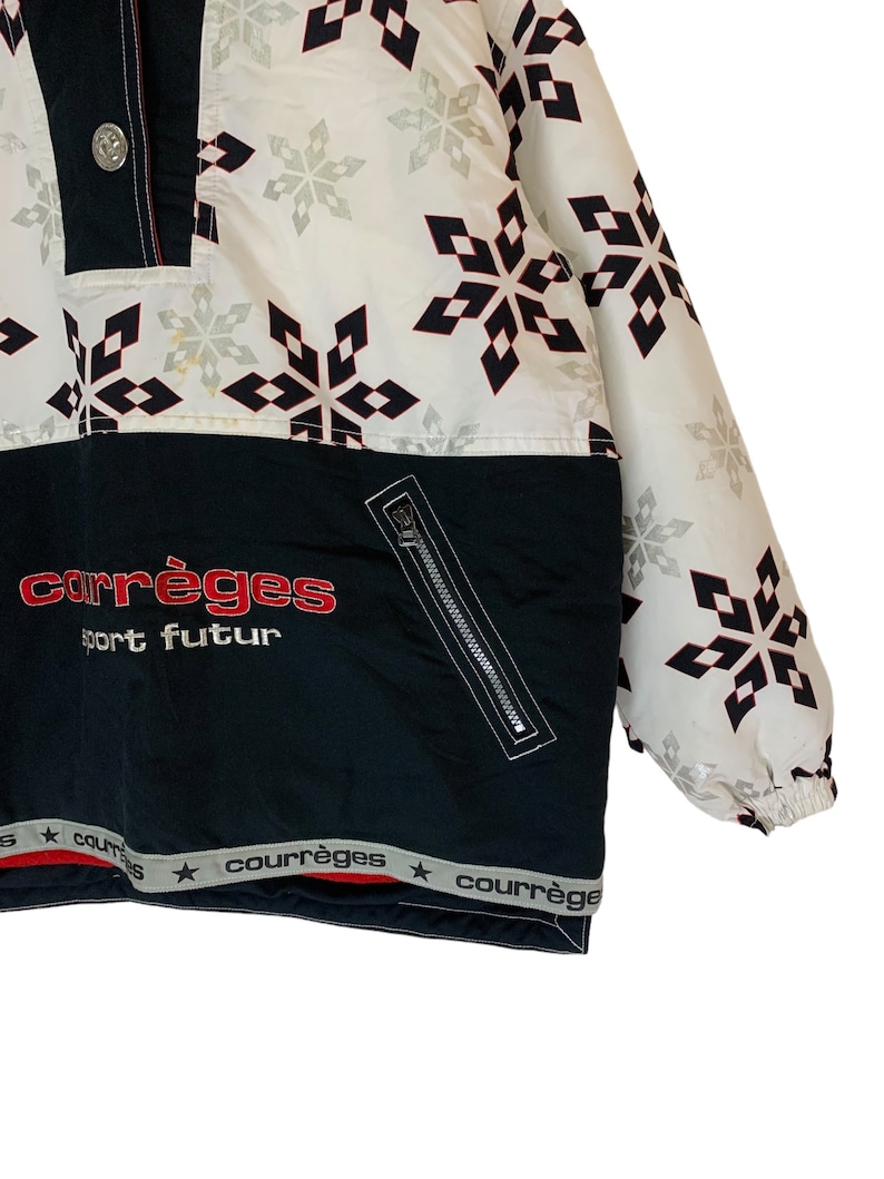 May include: A black and white ski jacket with a snowflake pattern. The jacket has a zipper closure and a red and white logo that says "courr&egrave;ges sport futur".