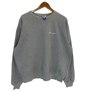 Op de afbeelding: Een grijs Champion sweatshirt met een klein geborduurd logo op de voorkant. Het sweatshirt heeft een ronde hals en lange mouwen.