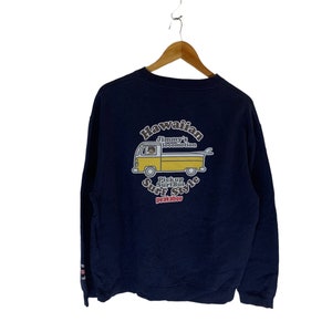 Könnte beinhalten: Ein marineblauer Sweatshirt mit einem gelben und weißen Aufdruck eines Vans mit einem Surfbrett auf dem Dach. Der Aufdruck lautet "Hawaiian Jimmy's Locomotion Pickup Surfbus Surf Style Peakaboo".