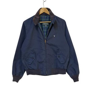 May include: Navy blue bomber jacket with a brown corduroy collar and a plaid lining. The jacket features two front pockets, a zipper closure, and a small embroidered logo on the chest. The cuffs and hem are ribbed.