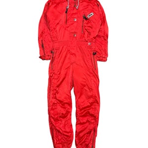 May include: A red ski suit with a white zipper and a white logo that says "Zima" on the chest.