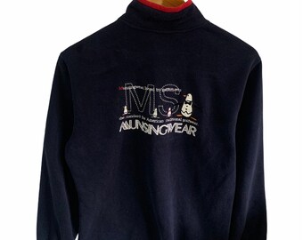 May include: Navy blue long-sleeved sweatshirt with a mock neck and red trim. The sweatshirt features the embroidered text "MS MUNSINGWEAR" with penguin graphics. The text "the standard for American traditional golfwear" is also visible.