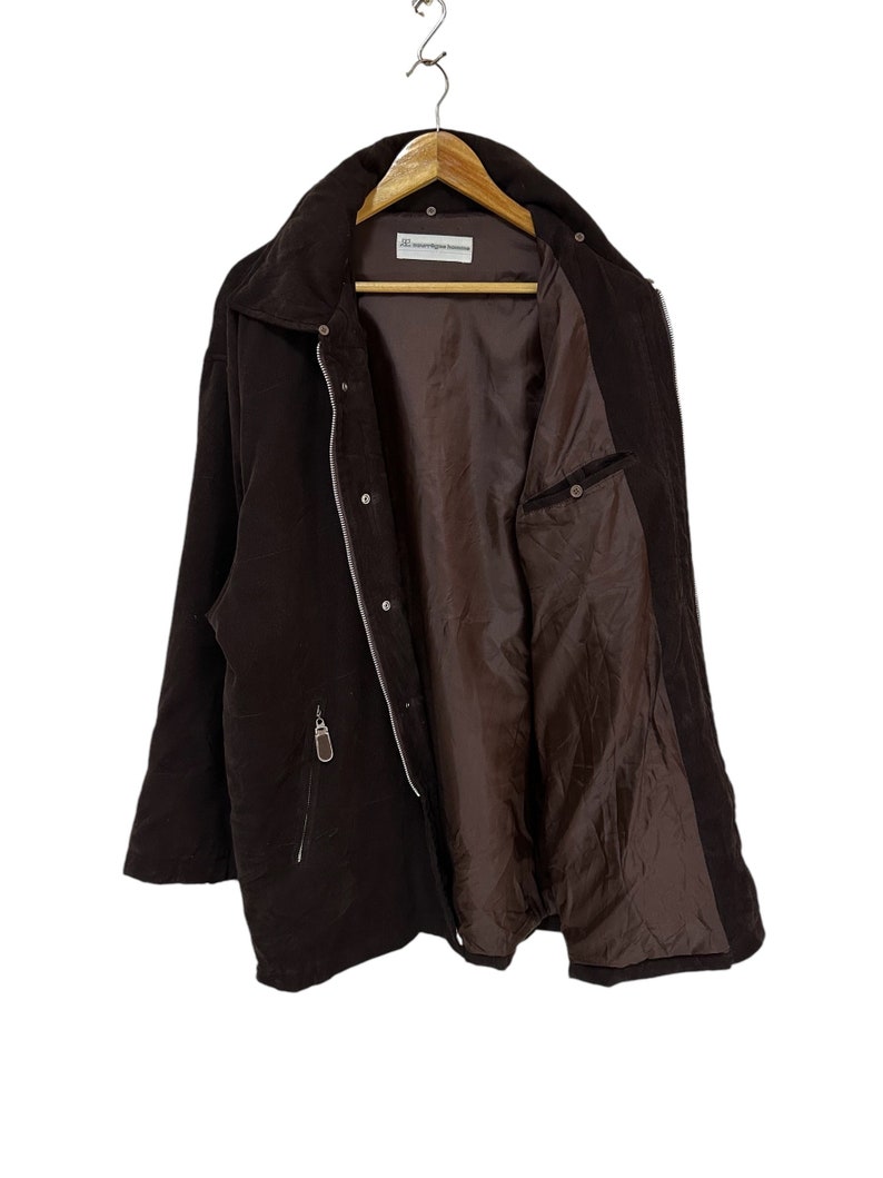 May include: A brown corduroy jacket with a zip fastening and a single pocket on the left side. The jacket is lined with a brown fabric and has a label that reads "Contemporary Classics".