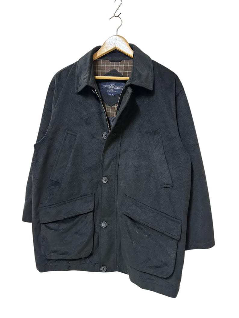 May include: A black long-sleeved jacket with a zip and button fastening. The jacket has two large pockets on the front and a plaid lining on the collar.