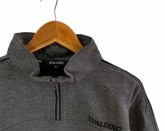 May include: A gray Spalding quarter-zip sweatshirt with black trim and the Spalding logo on the front.