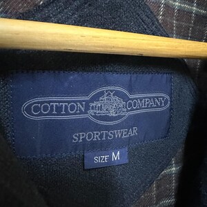 May include: A blue label with white text that reads "Cotton  Company  Sportswear" and "Size M".