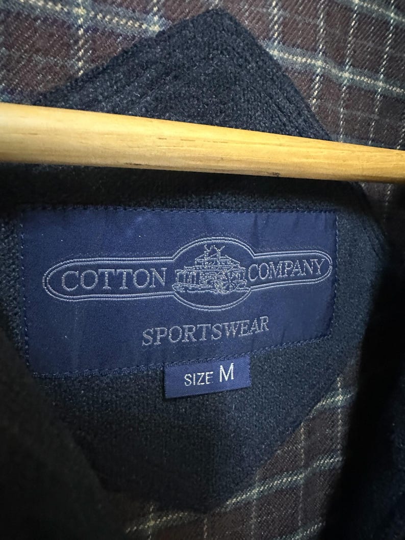 May include: A blue label with white text that reads "Cotton  Company  Sportswear" and "Size M".