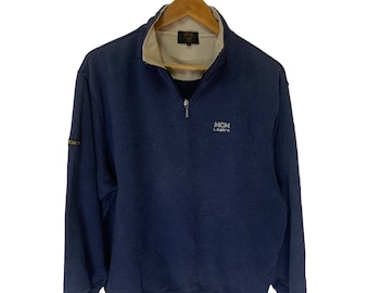May include: A navy blue sweatshirt with a half-zip closure and a MCM Leathers logo on the front. The sweatshirt has a beige lining around the collar.