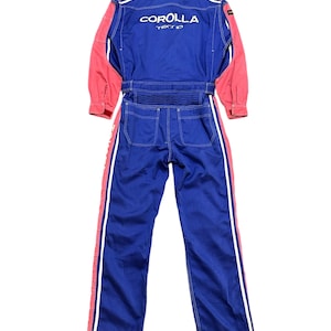 Op de afbeelding: Blauw en roze racepak met witte strepen aan de zijkanten. Het pak heeft de tekst "COROLLA TECHNO" op de rug.