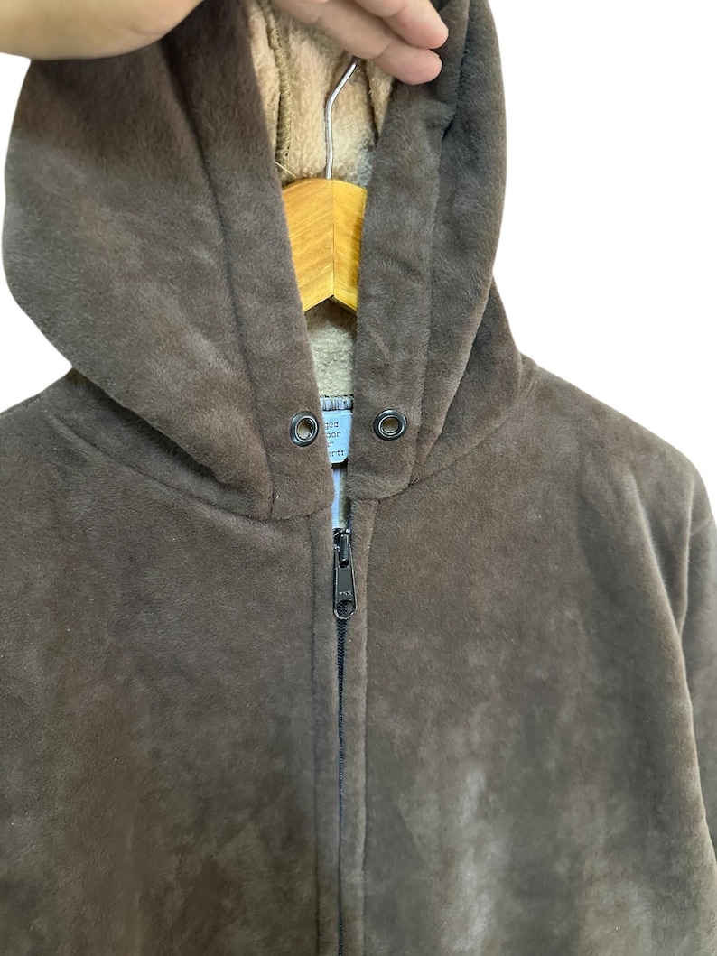 Puede incluir: Una sudadera con capucha de color marr&oacute;n de vell&oacute;n con cierre de cremallera. La sudadera tiene un forro suave y peludo.