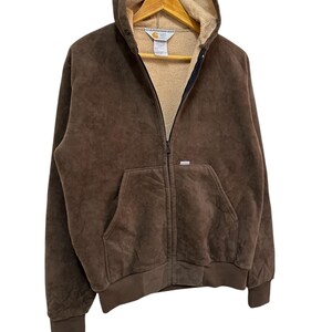 Puede incluir: Una sudadera con capucha marr&oacute;n con cierre de cremallera. La sudadera tiene un forro de polar y un peque&ntilde;o logotipo en el pecho izquierdo.