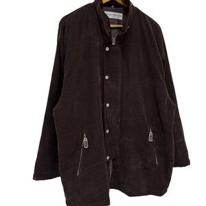 May include: A brown corduroy jacket with a zip and button fastening. The jacket has two zipped pockets on the front and a stand-up collar.