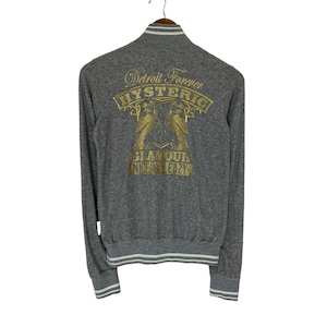 May include: Gray long-sleeve sweatshirt with a white ribbed collar and cuffs. The back of the sweatshirt features a gold embroidered design that says "Detroit Forever Hysteric Glamour 1972".