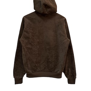 Puede incluir: Una sudadera con capucha marr&oacute;n con un tejido suave y texturizado. La sudadera tiene una capucha con cord&oacute;n y mangas largas.