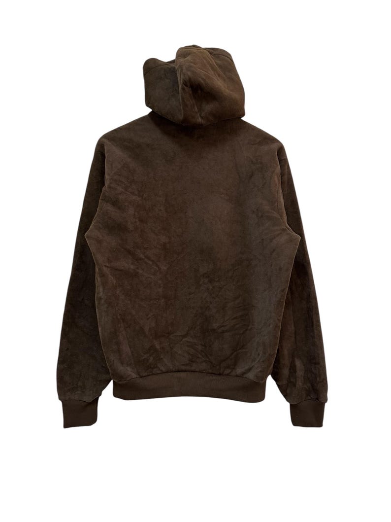 Puede incluir: Una sudadera con capucha marr&oacute;n con un tejido suave y texturizado. La sudadera tiene una capucha con cord&oacute;n y mangas largas.