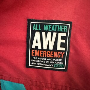 May include: A black and white patch with the text "ALL WEATHER AWE EMERGENCY" and "FOR RIDERS WHO PURSUE EXCELLENCE IN MECHANISM AND PERFORMANCE. YAMAHA".