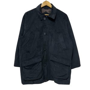 May include: A black suede jacket with a button-up front and two large pockets on the front. The jacket has a plaid lining.