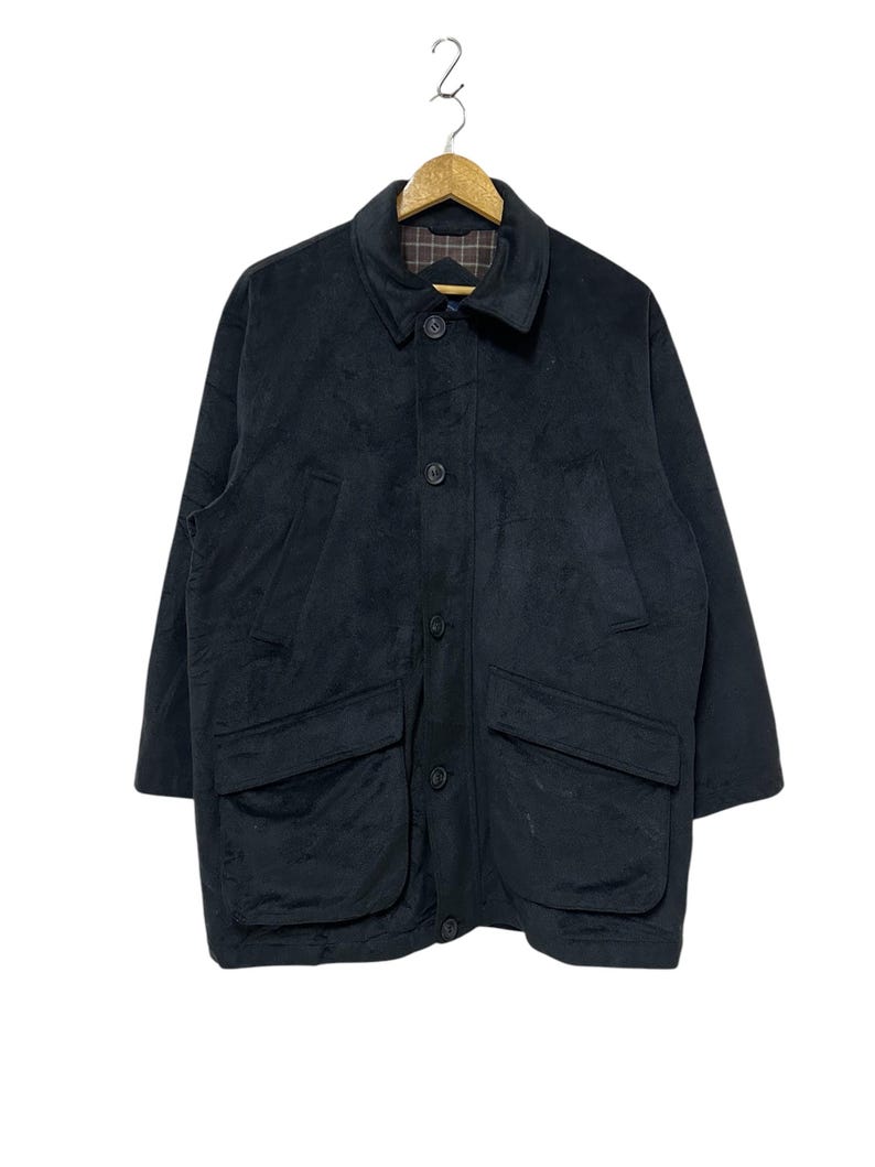 May include: A black suede jacket with a button-up front and two large pockets on the front. The jacket has a plaid lining.