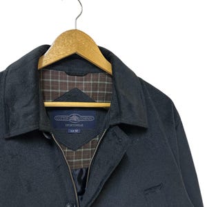 May include: A dark grey jacket with a zip fastening and a brown and white checked lining. The jacket has a label that reads "Cotton  Company  Sportswear  Size M".