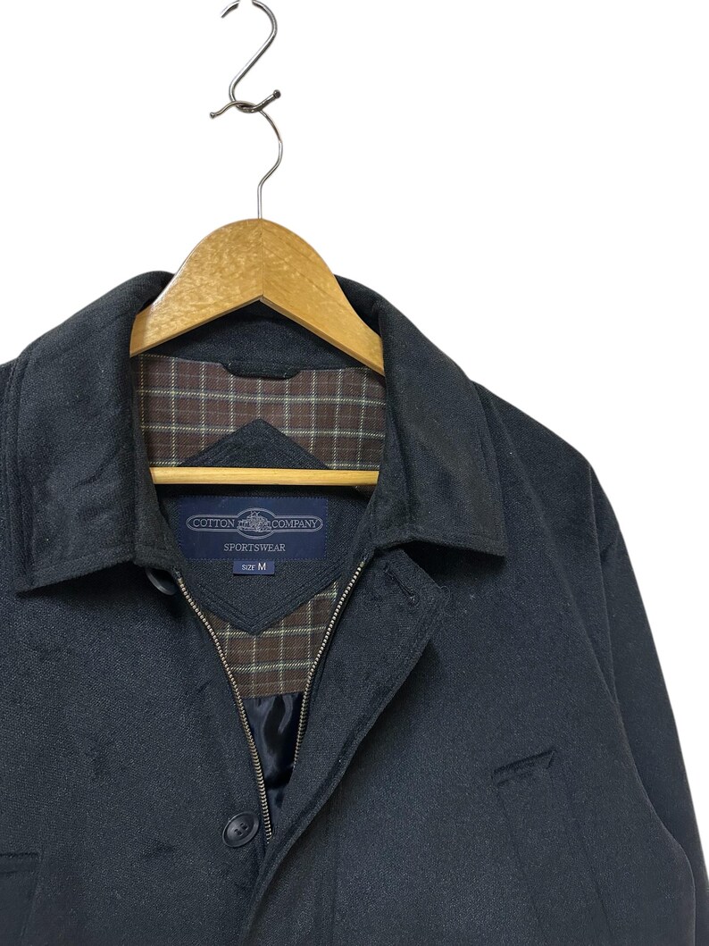 May include: A dark grey jacket with a zip fastening and a brown and white checked lining. The jacket has a label that reads "Cotton  Company  Sportswear  Size M".
