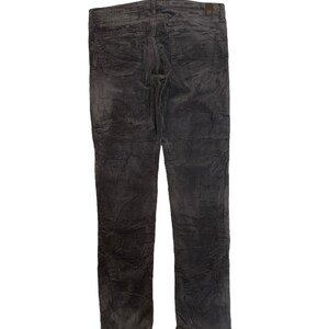 May include: Dark gray corduroy pants with a slim fit. The pants have a textured surface and a slightly distressed look.