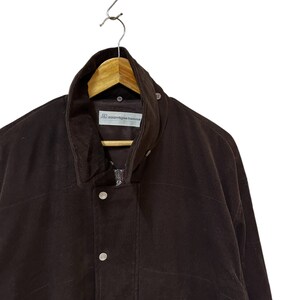 May include: A brown corduroy jacket with a zip fastening and button details. The jacket has a label that reads "comme des garcons homme."