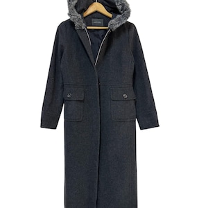 May include: A long, charcoal gray hooded coat with a faux fur trim around the hood. The coat has two large pockets on the front and a zipper closure.