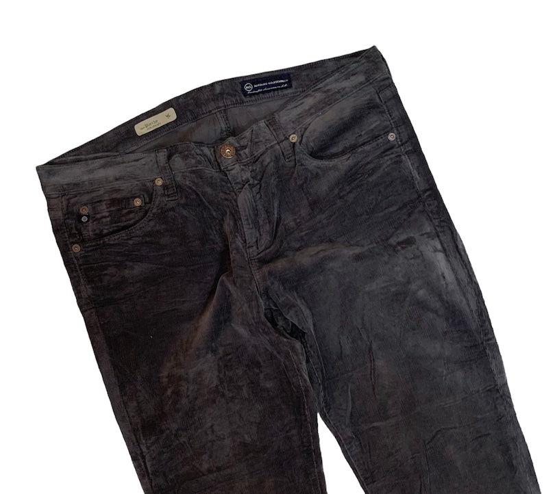 May include: Gray corduroy pants with a dark blue label that says "AG Adriano Goldschmied" on the back waistband.