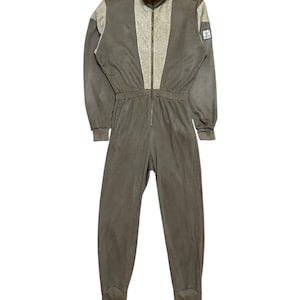 Puede incluir: Un mono de una pieza marrón y gris con cremallera en la parte delantera y un parche de logotipo en la manga.