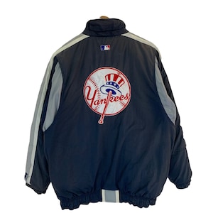 Könnte beinhalten: Eine dunkelblaue und graue reversible Jacke mit einem großen gestickten New York Yankees Logo auf der Rückseite. Das Logo zeigt einen Baseball, einen Schläger und eine Baseballkappe mit einer amerikanischen Flagge.