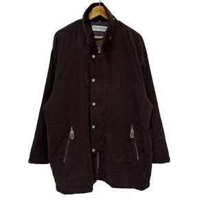 May include: A brown corduroy jacket with a zip and button fastening. The jacket has two zipped pockets on the front and a stand-up collar.