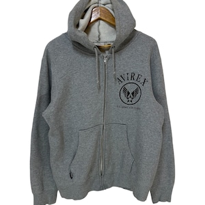 May include: A gray zip-up hoodie with a black embroidered logo that says "AVIREX U.S. ARMY AIR CORPS".