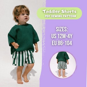 Könnte beinhalten: Ein Kleinkind trägt ein grünes Oberteil und gestreifte Shorts mit weißen und grünen vertikalen Streifen. Die Shorts haben eine Cargotasche. Der Text im Bild lautet "Toddler Shorts PDF Sewing Pattern" und die Größen US 12M-4Y, EU 86-104.