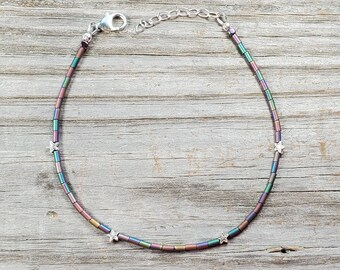May include: A silver chain anklet with iridescent beads and silver star charms.