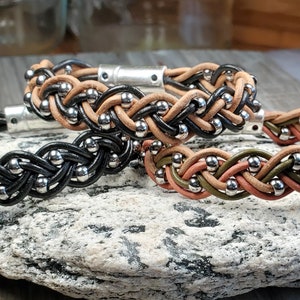 May include: Three braided leather bracelets with silver beads. The bracelets are in black, brown, and green.