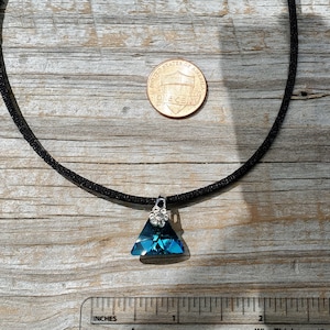 May include: A black choker necklace with a teal triangle pendant accented with silver rhinestones. The pendant is about the size of a US penny.
