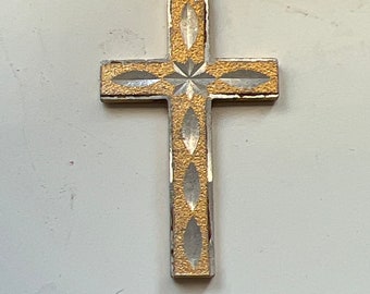 May include: A gold and silver cross pendant with a diamond pattern. The cross is a religious symbol.