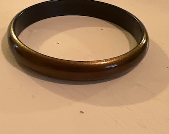 May include: A brown and black bangle bracelet with a shiny finish.