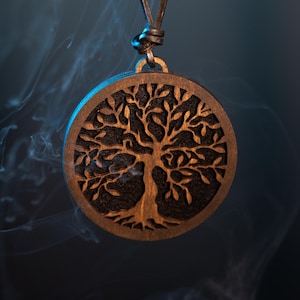 Könnte beinhalten: Eine Holz-Anhänger-Halskette mit einem Lebensbaum-Design. Der runde Anhänger hat einen detaillierten Baumausschnitt. Die Halskette hängt an einer dunkelbraunen Lederschnur. Der Hintergrund ist dunkelblau mit Rauchschwaden.