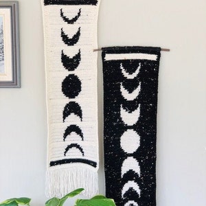 Puede incluir: Dos tapices de pared de crochet blanco y negro con flecos. Cada tapiz presenta un patr&oacute;n de lunas crecientes.