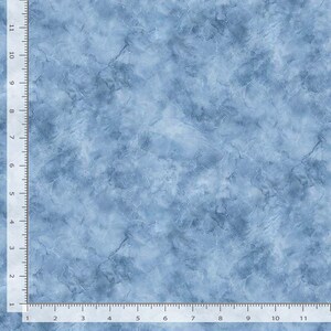 May include: A light blue fabric with a marbled pattern. The fabric has a textured appearance with darker blue veins and swirls throughout. The image includes a ruler along the edges, showing measurements in inches.