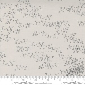 May include: A beige fabric with a repeating pattern of small black squares and rectangles. The fabric has a subtle texture and a ruler with markings in inches is visible at the bottom of the image.